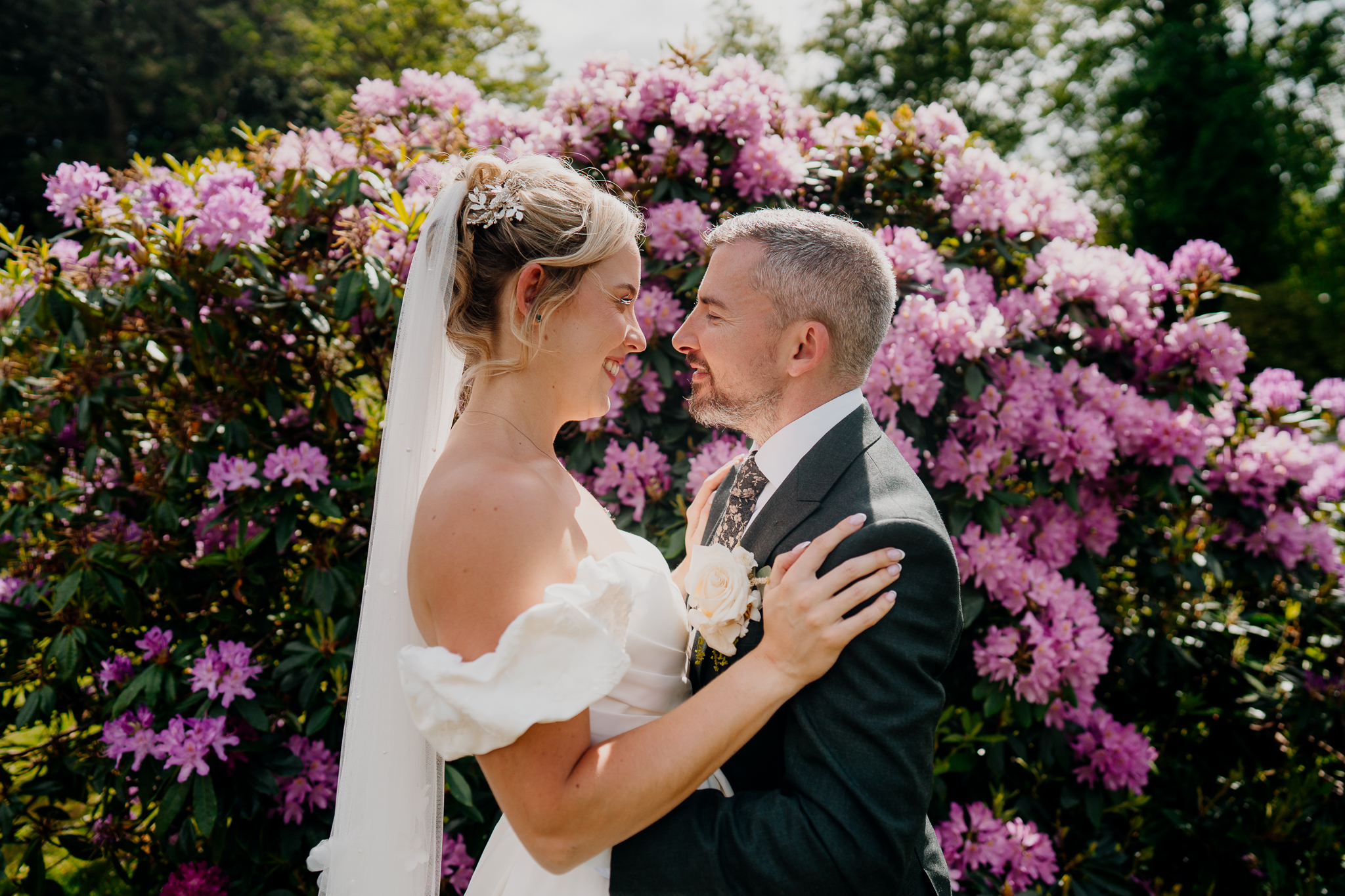 Bride and groom sharing an intimate moment beside pink flowering shrubs in the gardens of Markree Castle, Sligo.