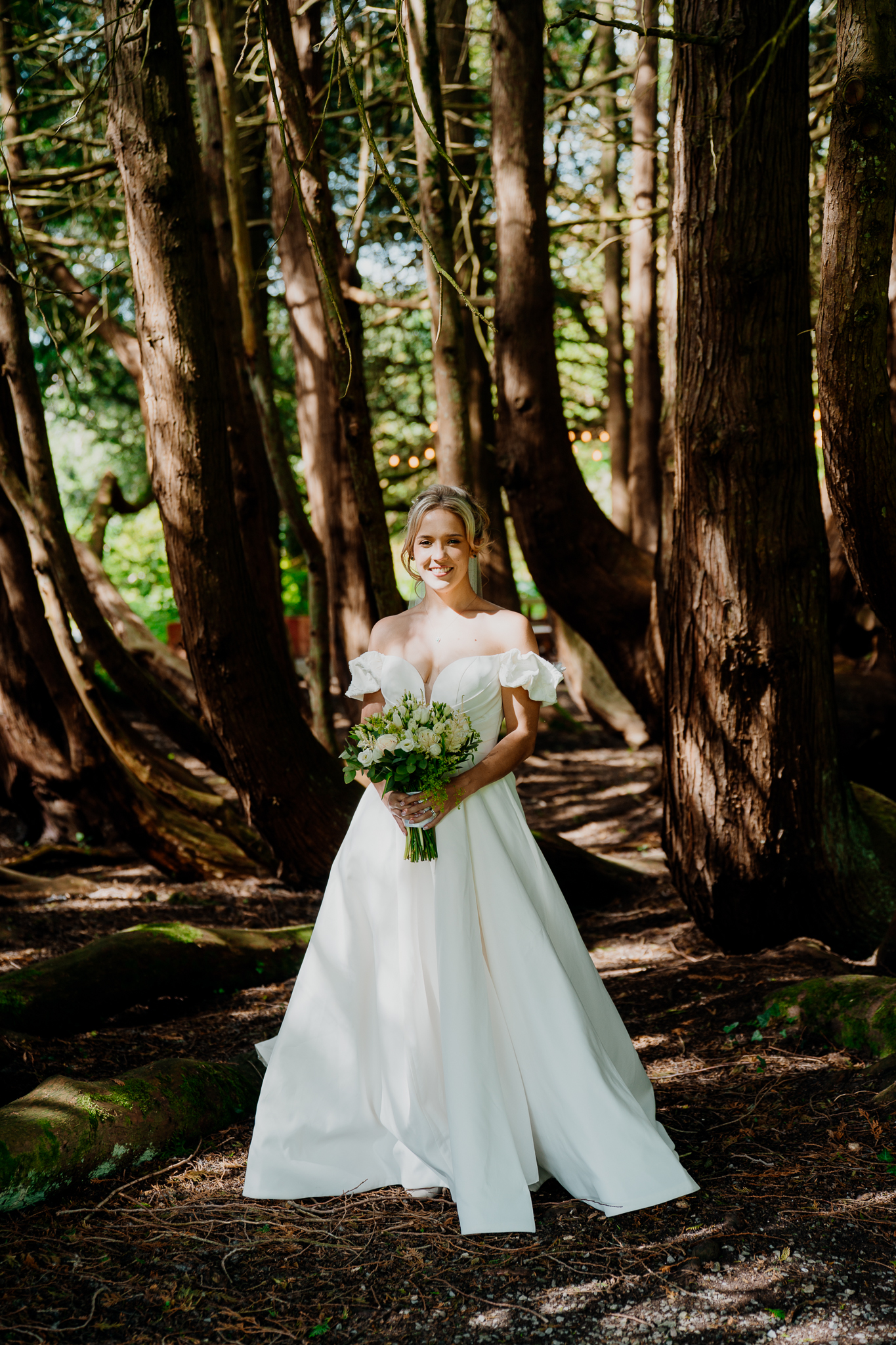 Bride Zoe holding her wedding bouquet among mature trees in the woodlands at Markree Castle, Sligo.