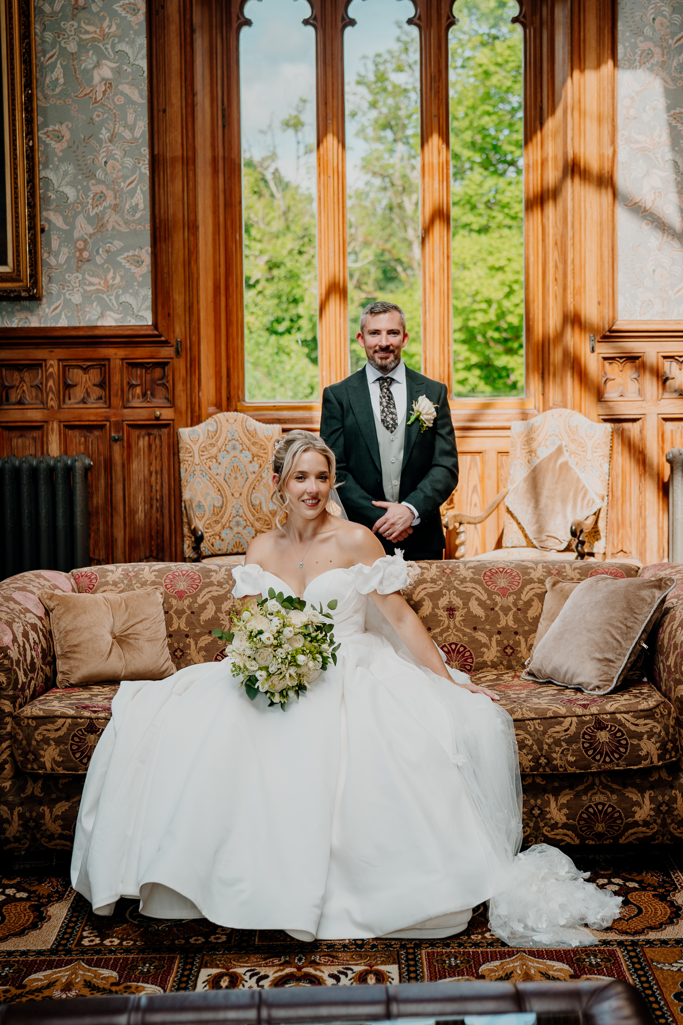 Bride seated beside groom in the wood-panelled Billiard Room at Markree Castle, with tall windows and antique interiors.