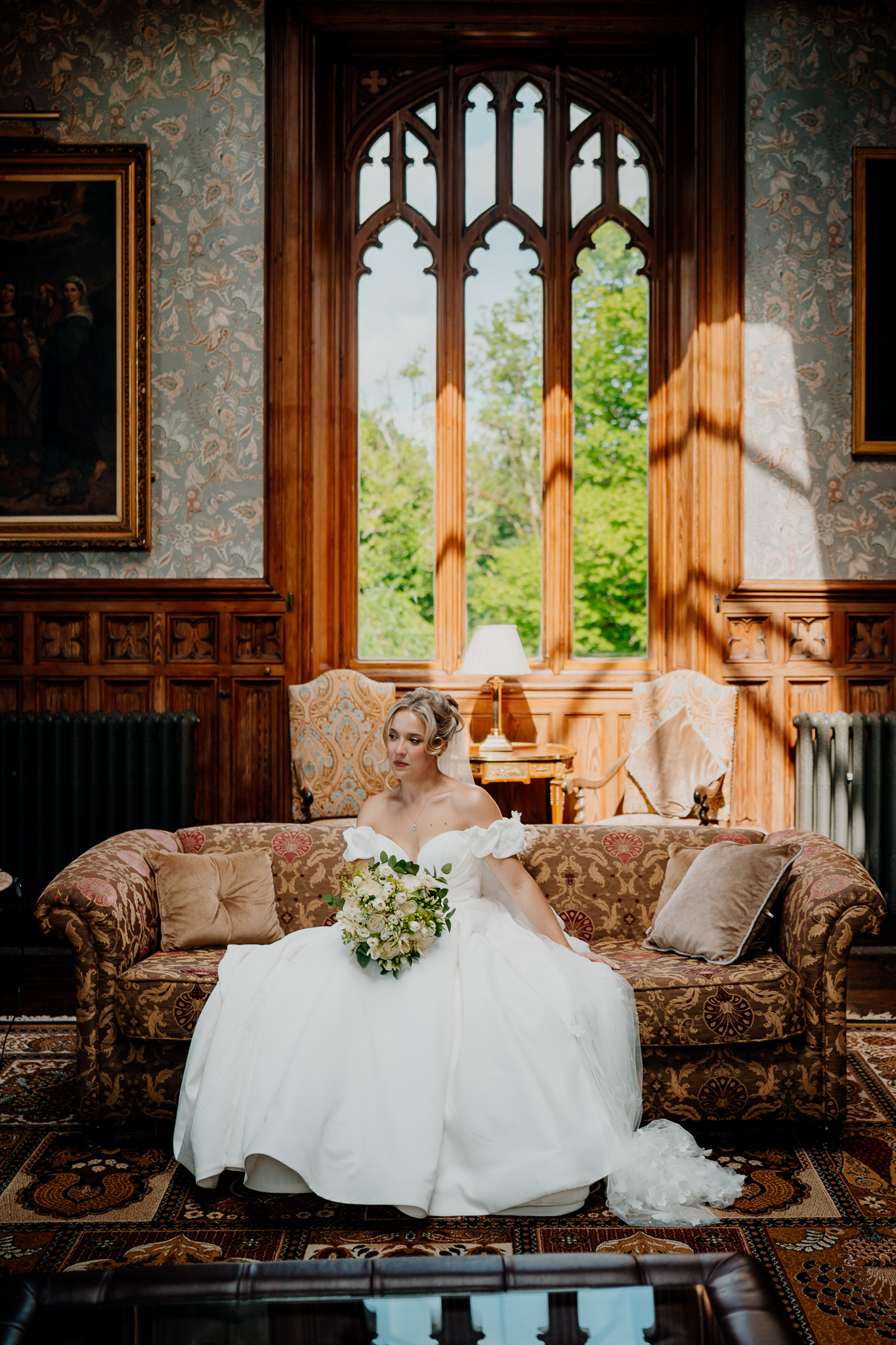 Bride Zoe seated beside a tall window in the Billiard Room at Markree Castle, surrounded by warm wood panelling.