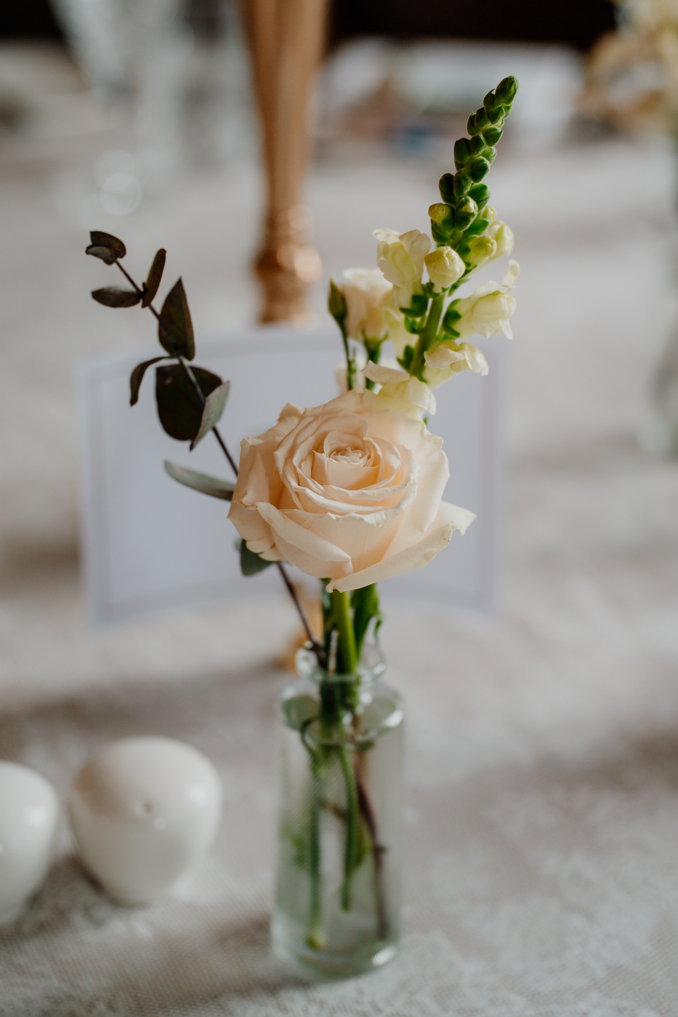 Close-up of a white rose and green foliage in a wedding floral arrangement at Markree Castle dining room.