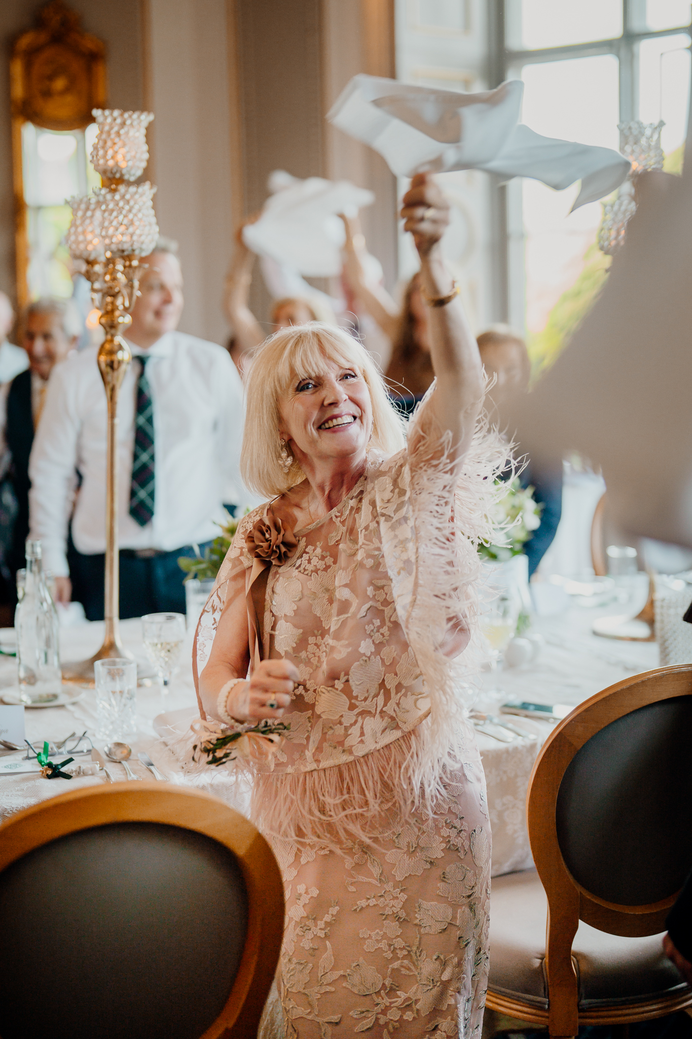 Smiling wedding guest raising a white napkin during the bride and groom's entrance to the Dining Room at Markree Castle.