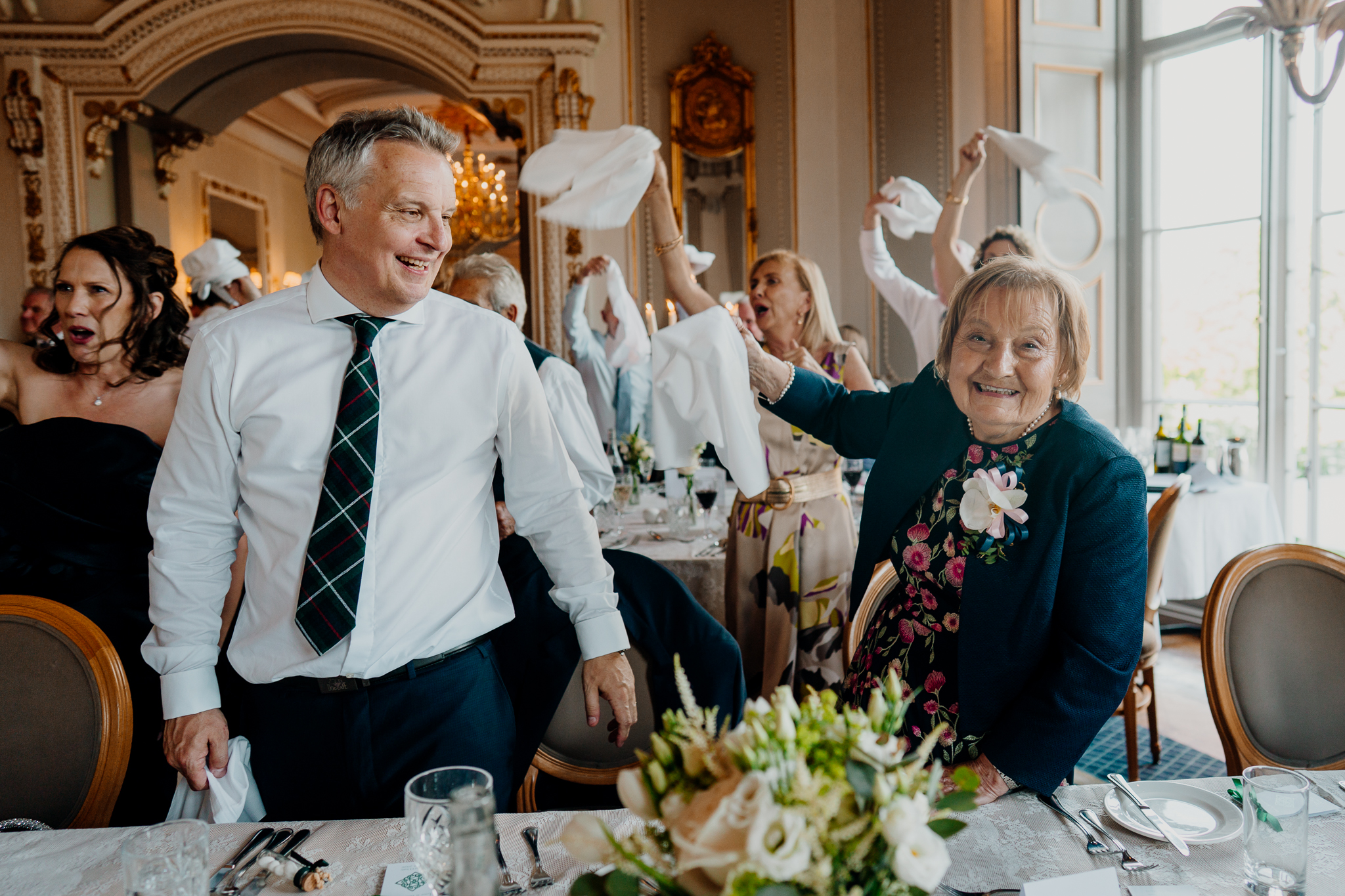 Wedding guests smiling and waving white napkins at their tables during the reception entrance at Markree Castle.