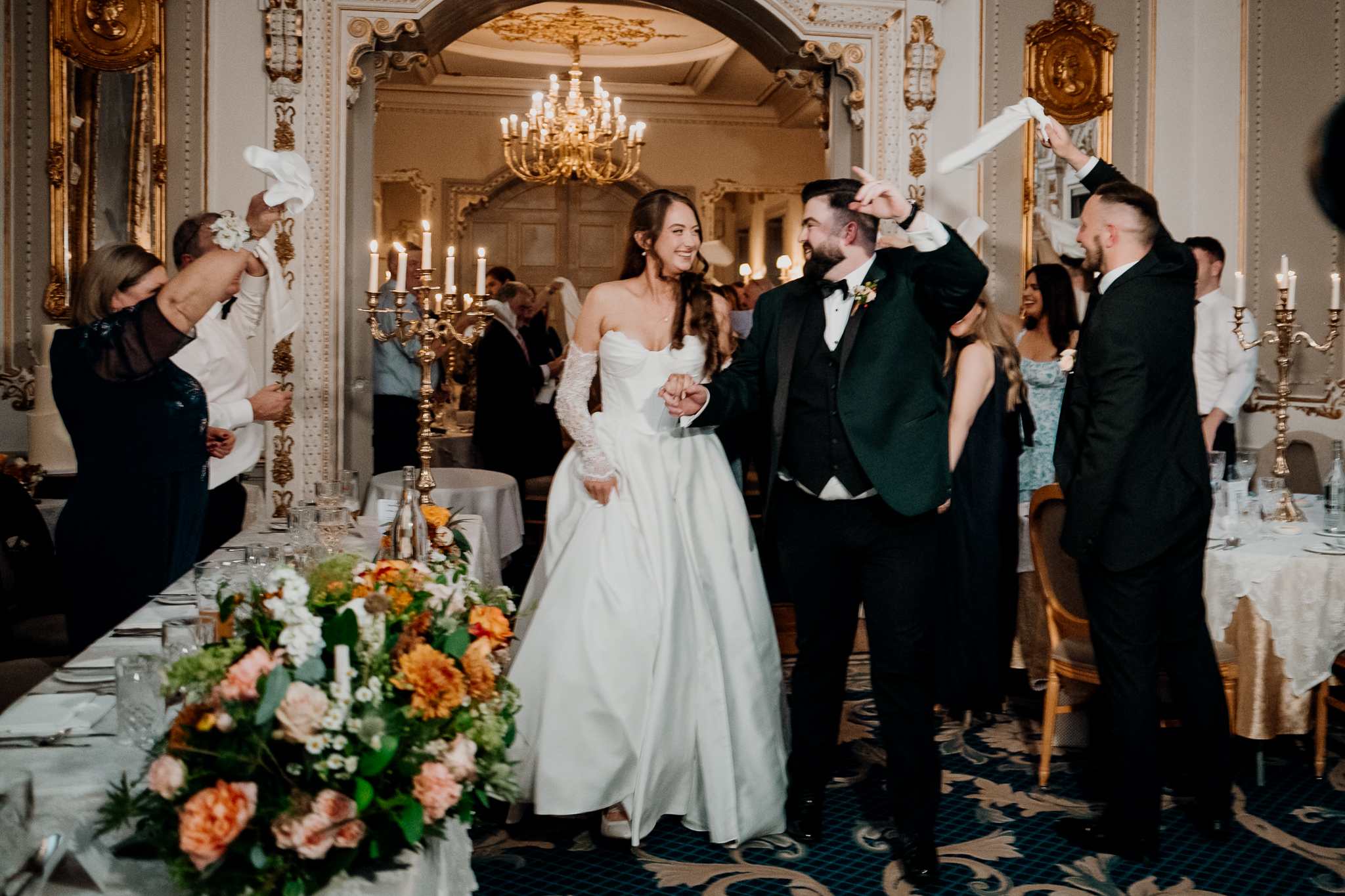 Bride and groom entering the wedding dining room at Markree Castle as guests cheer and raise their arms.
