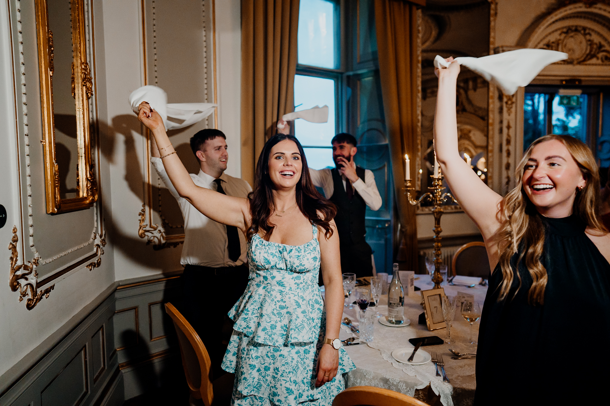 Wedding guests cheering with their arms raised during the bride and groom's entrance into Markree Castle's dining room.
