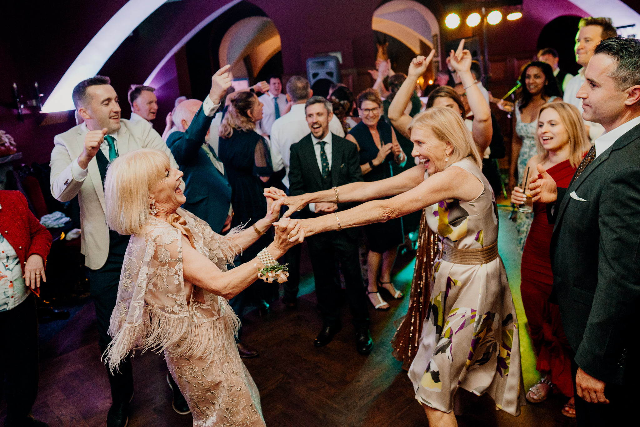 Bride and wedding guests dancing together on a lively indoor dance floor at Markree Castle, with hands raised and colourful evening lights.