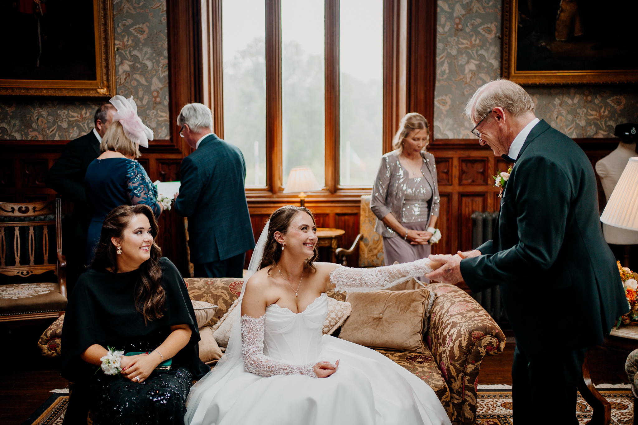 Wedding guests chatting together beside tall windows in the Billiard Room at Markree Castle.