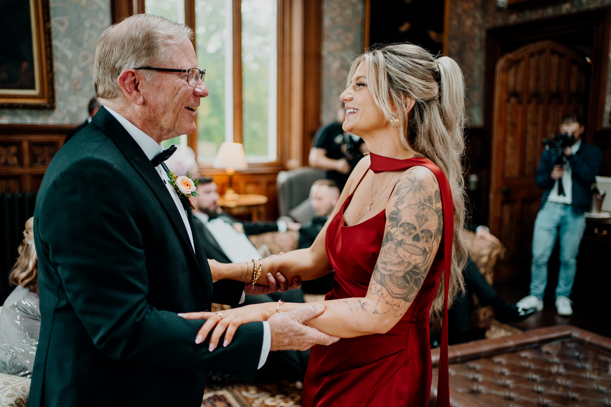 Smiling female wedding guest in a burgundy dress talking with an older gentleman inside Markree Castle.