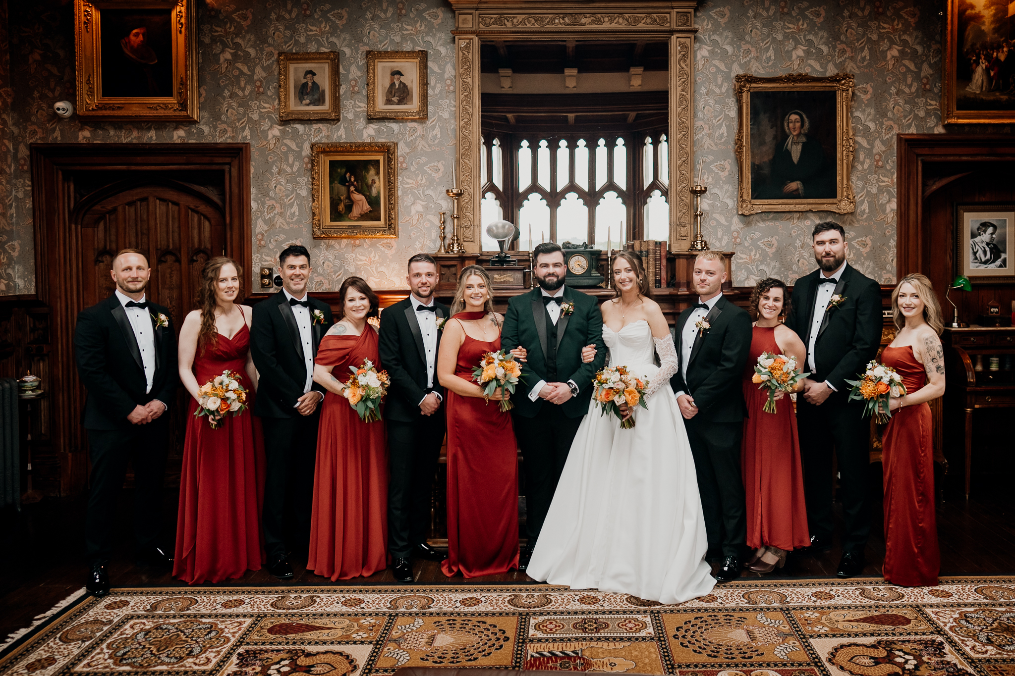 Bride and wedding party posing together indoors at Markree Castle, with bridesmaids in burgundy dresses and groomsmen in dark green suits.