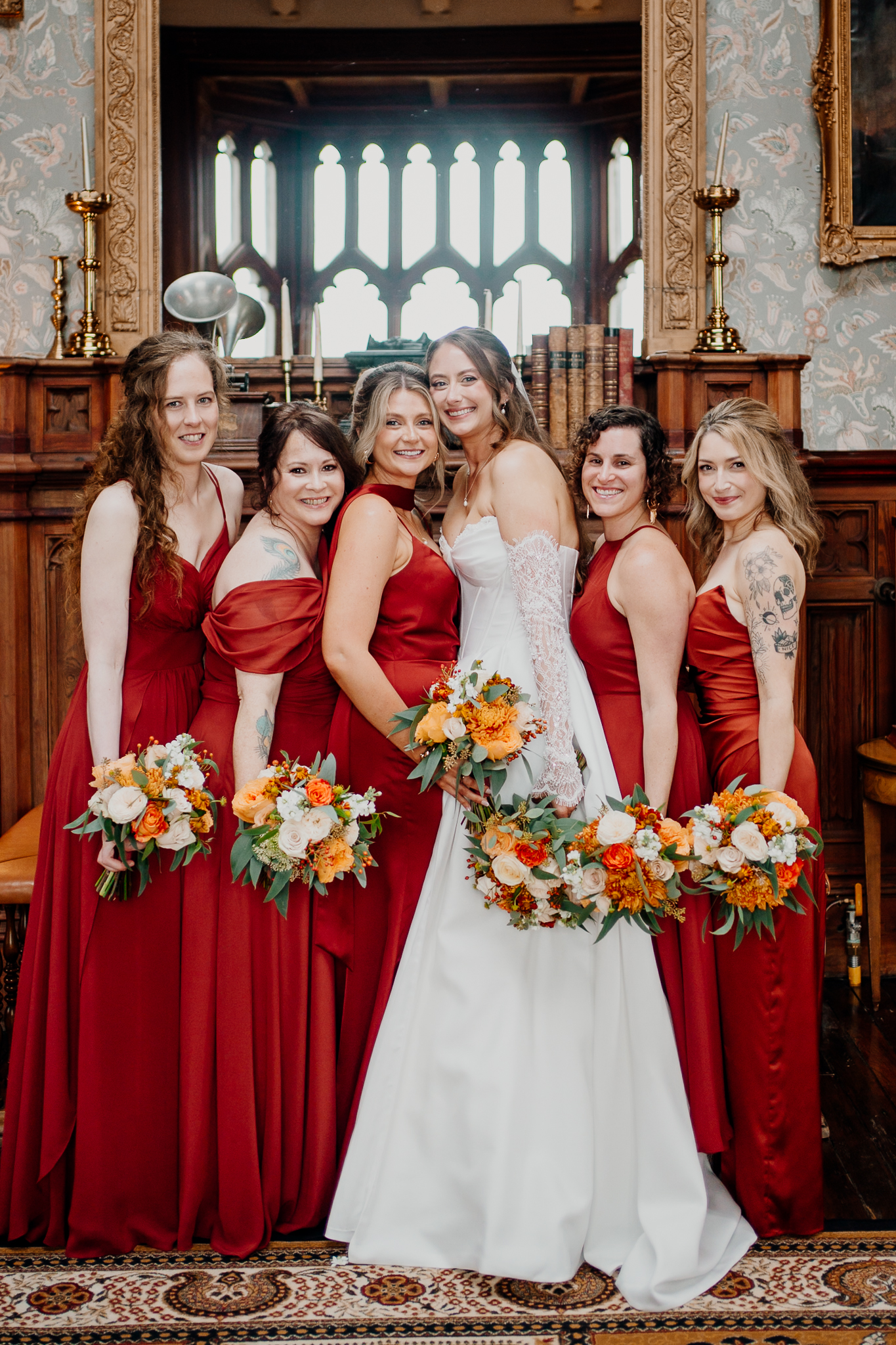 Bride and bridesmaids in burgundy dresses posing together inside the Billiard Room at Markree Castle.
