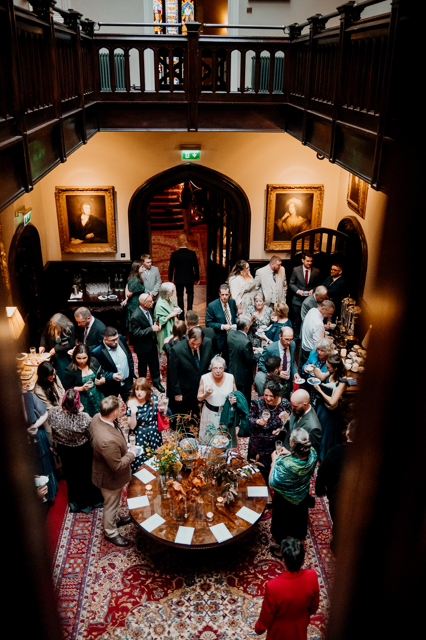 Wedding guests socialising during an indoor drinks reception beneath an arched doorway at Markree Castle.