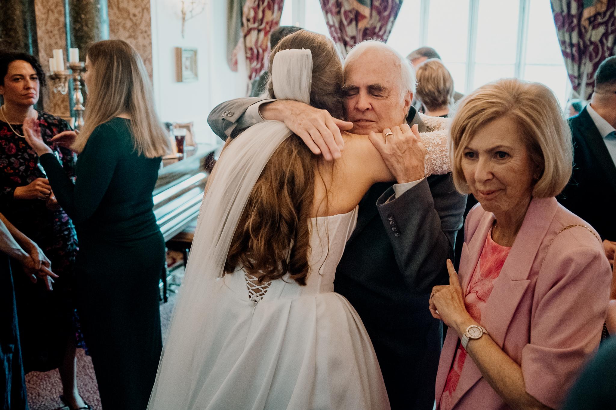 Wedding guests sharing a warm family embrace during the indoor drinks reception at Markree Castle.