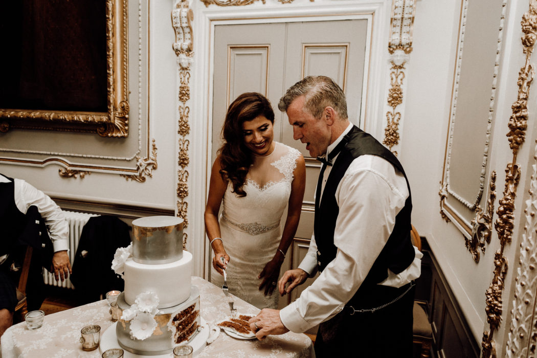 A man and a woman standing in front of a wedding cake